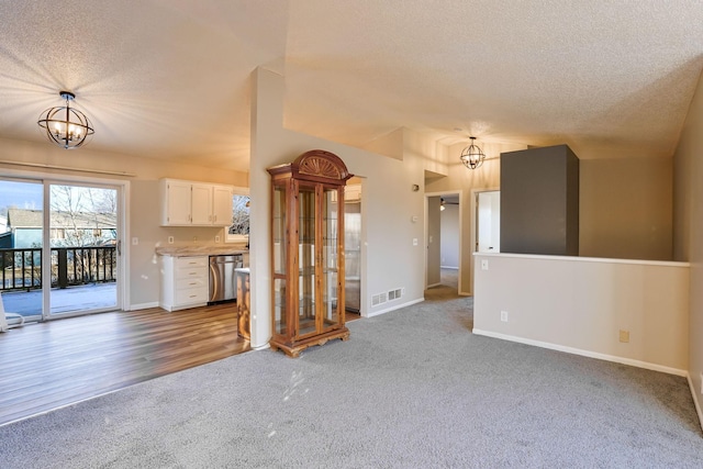 unfurnished living room with hardwood / wood-style flooring, lofted ceiling, a textured ceiling, and an inviting chandelier