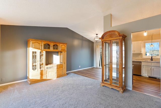 unfurnished living room with hardwood / wood-style floors, vaulted ceiling, and sink