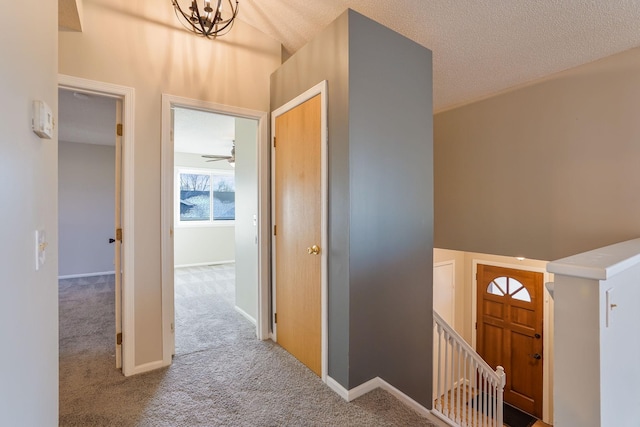 carpeted foyer featuring a textured ceiling, vaulted ceiling, and ceiling fan