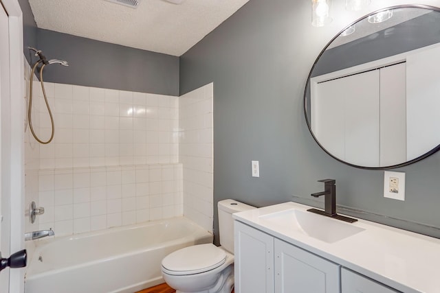 full bathroom with vanity, toilet, a textured ceiling, and tiled shower / bath