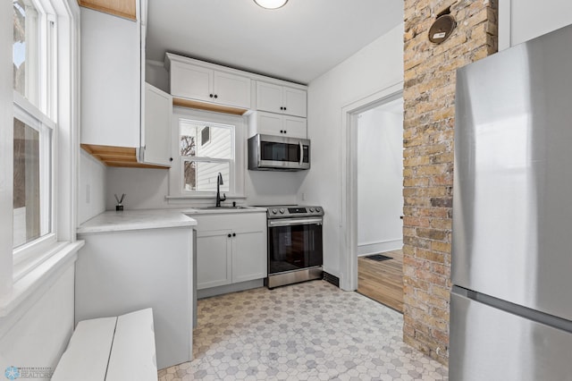 1018 11th St S, Fargo, ND 58103 - kitchen featuring appliances with stainless steel finishes, white cabinetry, light countertops, and light floors