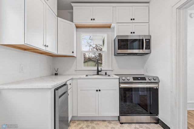 kitchen with light stone counters, appliances with stainless steel finishes, sink, and white cabinets