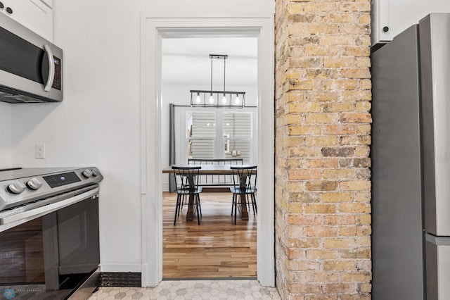 kitchen with pendant lighting, white cabinets, and appliances with stainless steel finishes