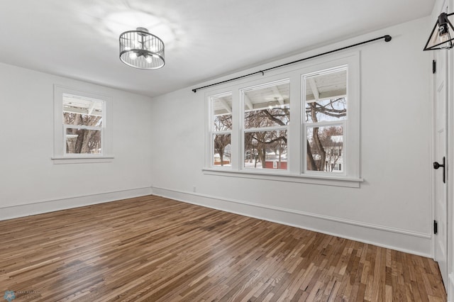 unfurnished room featuring hardwood / wood-style flooring, an inviting chandelier, and a wealth of natural light