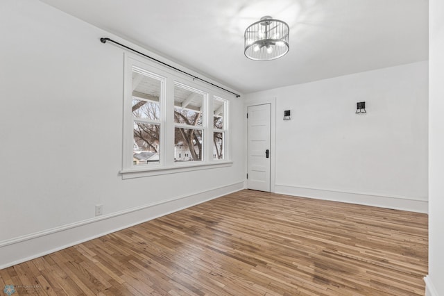 empty room with an inviting chandelier and light wood-type flooring