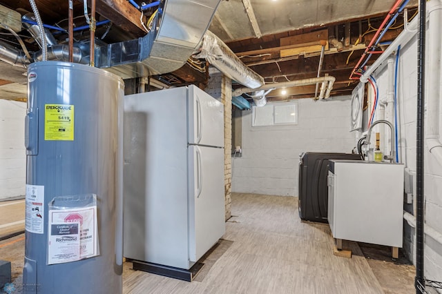 basement with washer / clothes dryer, water heater, and white fridge