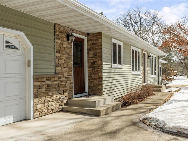 property entrance featuring stone siding and an attached garage