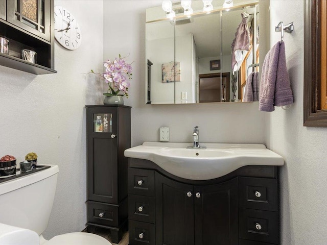 half bath featuring vanity and toilet