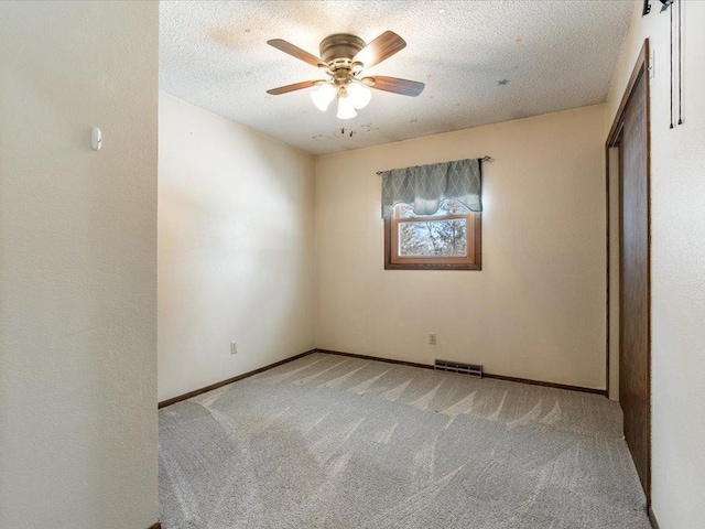 unfurnished bedroom featuring a textured ceiling, baseboards, visible vents, and light colored carpet