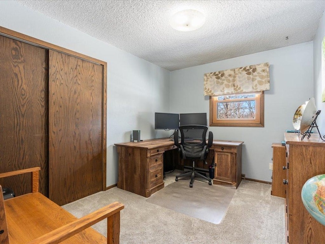 office area with light carpet, baseboards, and a textured ceiling