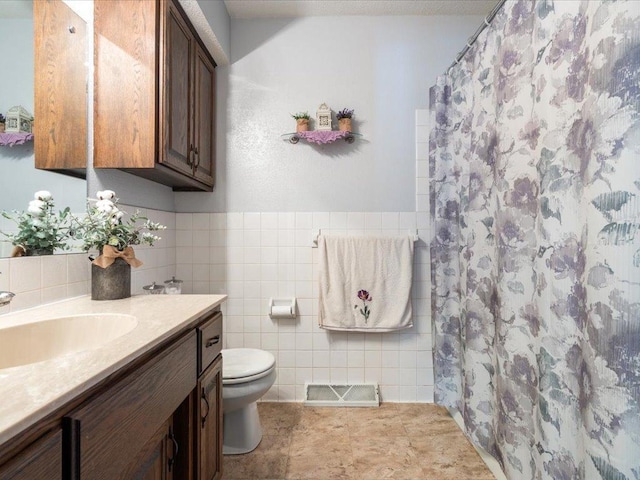 bathroom featuring tile patterned flooring, toilet, vanity, visible vents, and tile walls