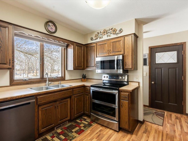 kitchen featuring light wood-type flooring, appliances with stainless steel finishes, light countertops, and a sink