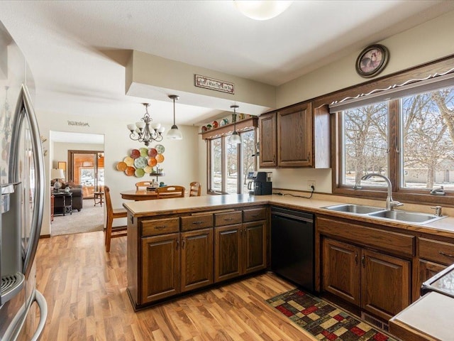 kitchen with light wood finished floors, freestanding refrigerator, a sink, a peninsula, and dishwashing machine