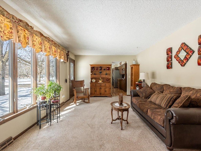 living area with baseboards, visible vents, a textured ceiling, and light colored carpet