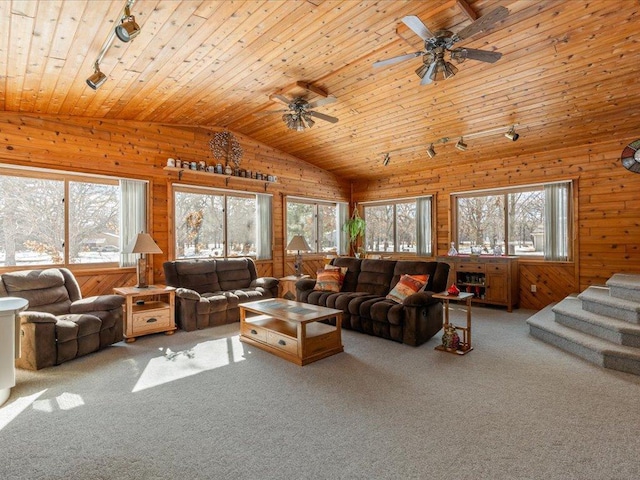 living room featuring lofted ceiling, carpet, a wealth of natural light, and wooden walls