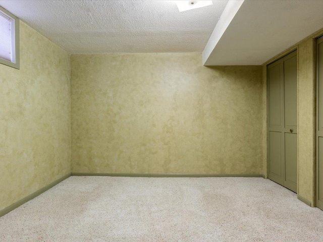 finished basement with light carpet and a textured ceiling