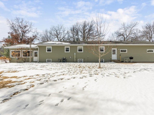 snow covered house featuring cooling unit