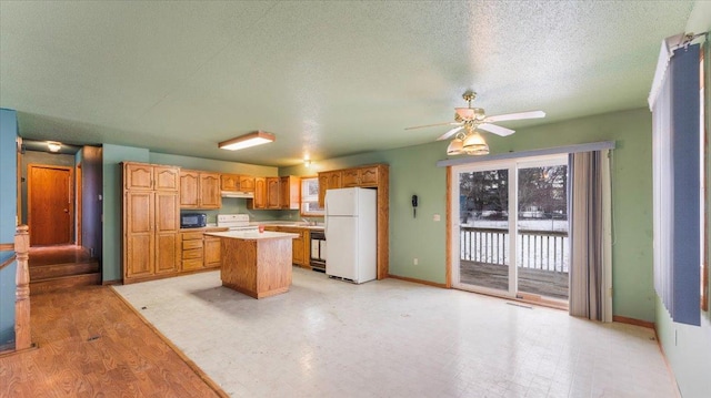 kitchen featuring a kitchen island, white fridge, ceiling fan, a textured ceiling, and electric stove