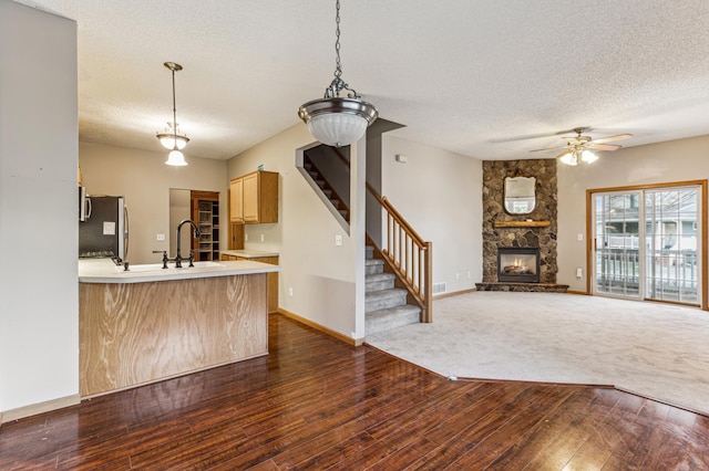 kitchen featuring stainless steel refrigerator, kitchen peninsula, dark wood-type flooring, and a textured ceiling