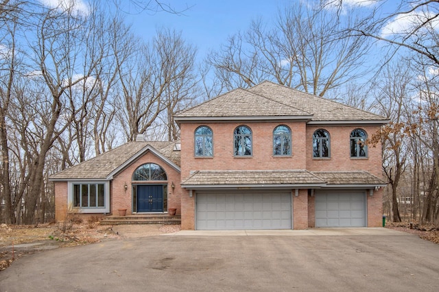 traditional-style home with aphalt driveway, brick siding, and a garage