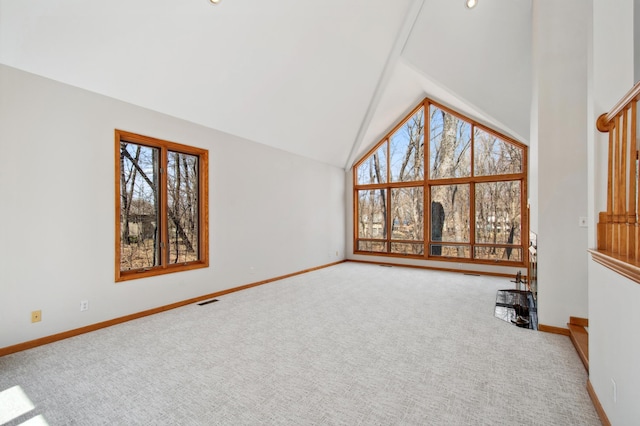 unfurnished living room featuring high vaulted ceiling, a healthy amount of sunlight, visible vents, and carpet