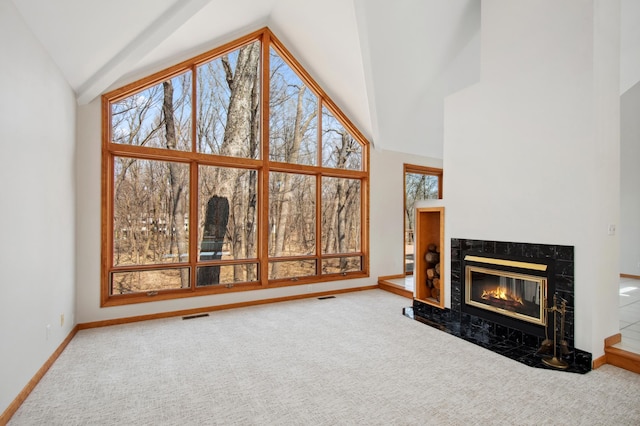 unfurnished living room featuring high vaulted ceiling, a premium fireplace, visible vents, and carpet