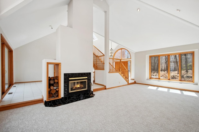 unfurnished living room with high vaulted ceiling, baseboards, carpet flooring, and stairs