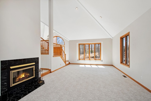 unfurnished living room featuring stairway, a premium fireplace, baseboards, carpet flooring, and visible vents