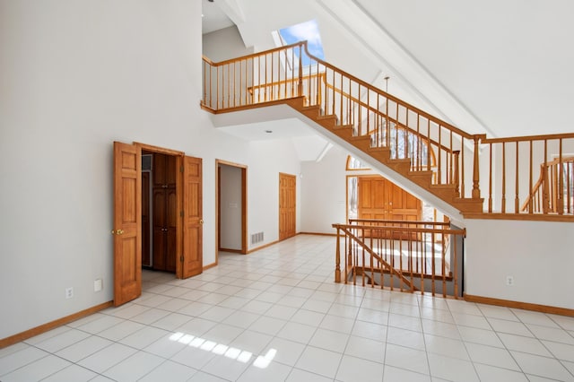 staircase featuring high vaulted ceiling, baseboards, tile patterned flooring, and visible vents