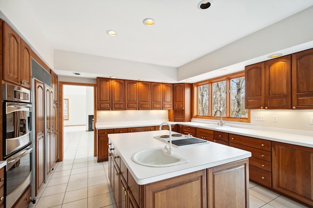 kitchen with recessed lighting, light countertops, a sink, a kitchen island with sink, and white electric stovetop