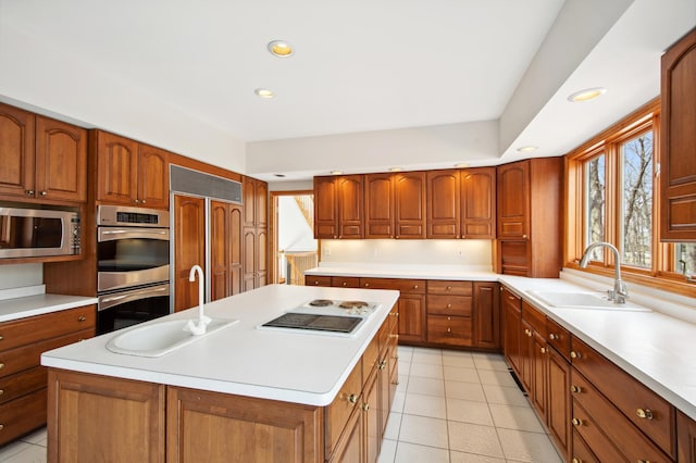 kitchen featuring built in appliances, light countertops, and a sink
