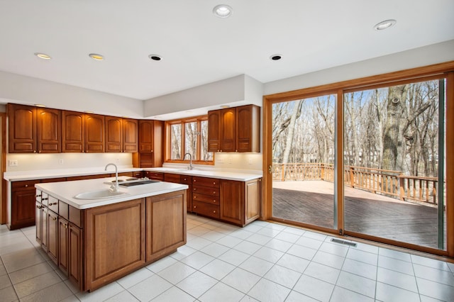 kitchen with light countertops, visible vents, a sink, and an island with sink