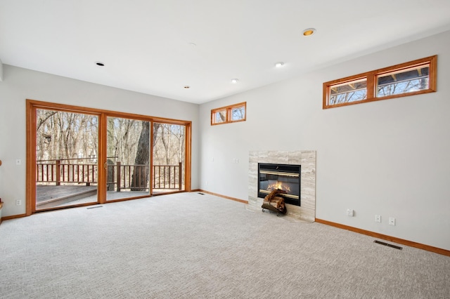 unfurnished living room with a premium fireplace, baseboards, carpet flooring, visible vents, and recessed lighting