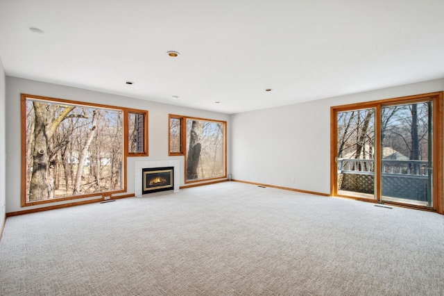 unfurnished living room featuring carpet floors, a healthy amount of sunlight, and baseboards