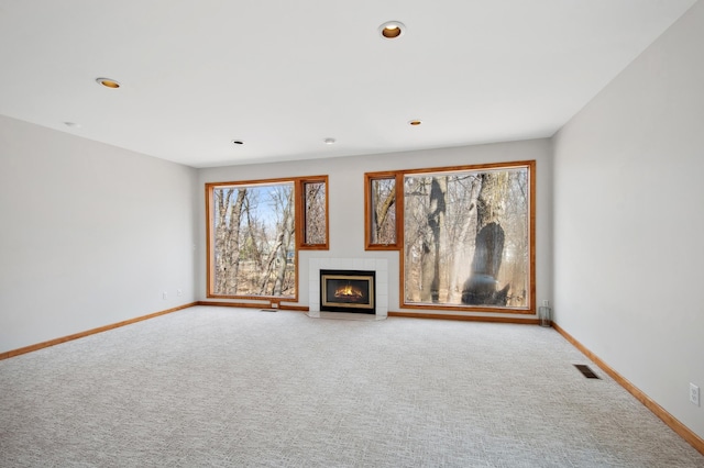 unfurnished living room with baseboards, carpet flooring, a tile fireplace, and visible vents