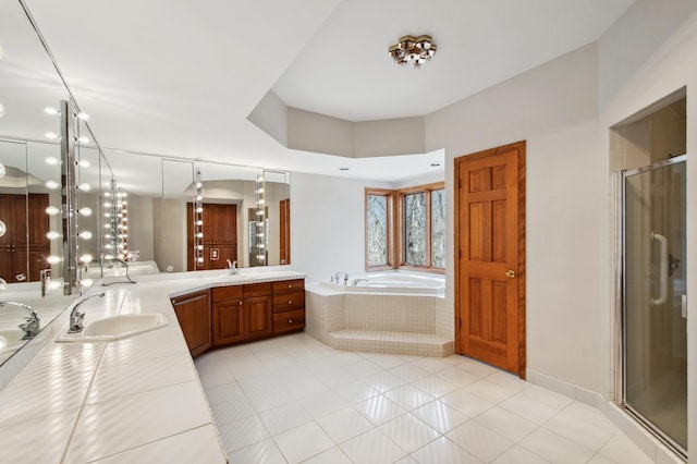bathroom with tile patterned floors, a sink, double vanity, a stall shower, and a garden tub