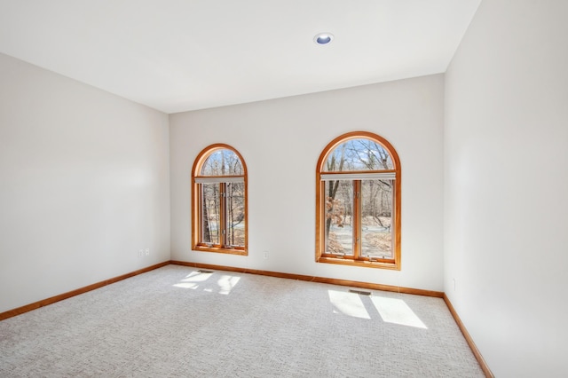 carpeted spare room with visible vents and baseboards