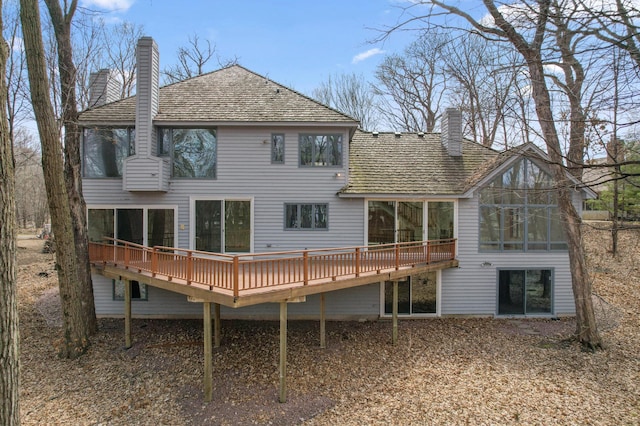 rear view of property with a wooden deck, a sunroom, and a chimney