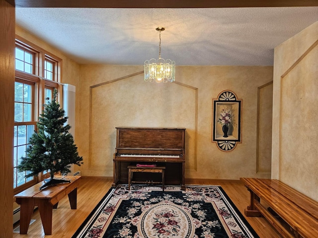 living area with a textured ceiling, hardwood / wood-style flooring, and a notable chandelier