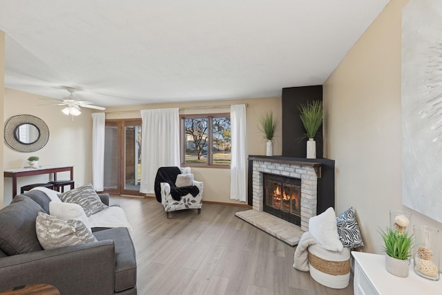 living room featuring ceiling fan, light wood-type flooring, and a fireplace