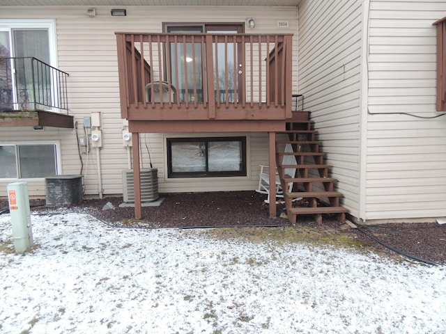 snow covered rear of property featuring central AC unit