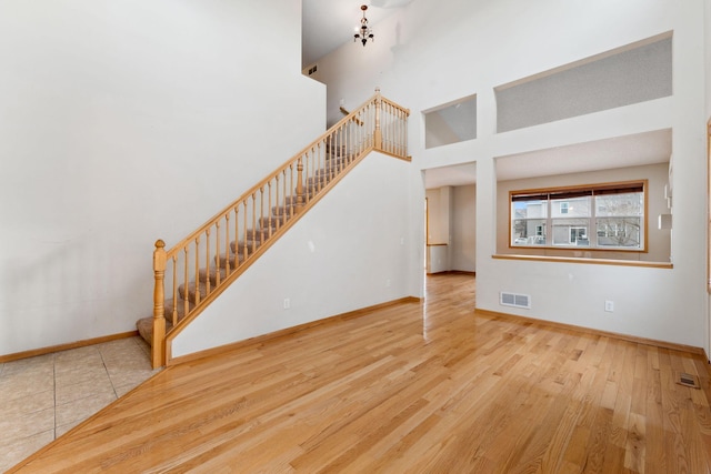 unfurnished living room featuring hardwood / wood-style floors and a towering ceiling