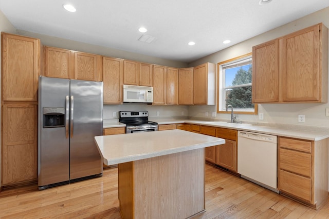 kitchen with sink, light brown cabinets, light hardwood / wood-style flooring, a kitchen island, and appliances with stainless steel finishes