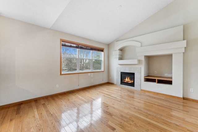 unfurnished living room featuring light hardwood / wood-style floors, lofted ceiling, and a fireplace