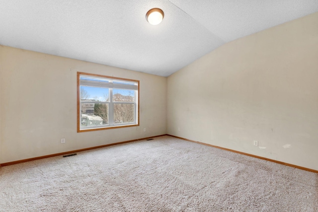 carpeted empty room with a textured ceiling and vaulted ceiling