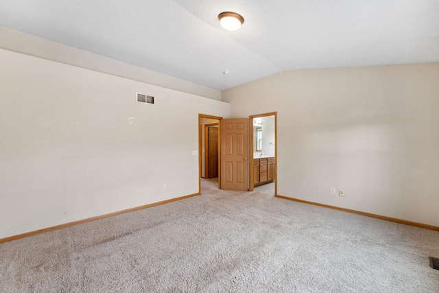 unfurnished room featuring light colored carpet and vaulted ceiling