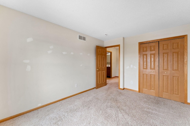 unfurnished bedroom with a closet, light colored carpet, and a textured ceiling