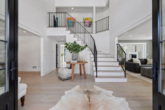 entryway with stairway, wood finished floors, baseboards, and a towering ceiling