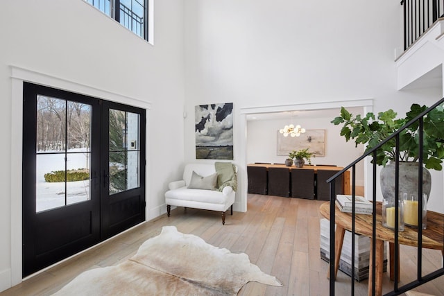 entryway with stairs, hardwood / wood-style floors, french doors, a towering ceiling, and a notable chandelier