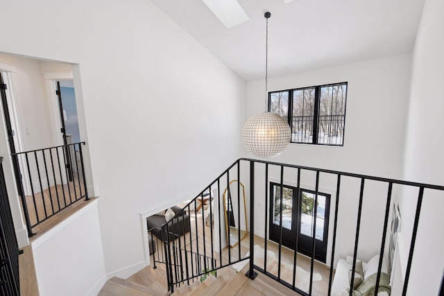 stairs with a skylight, a notable chandelier, a healthy amount of sunlight, and a high ceiling